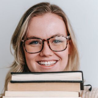 smiling woman in eyeglasses with books