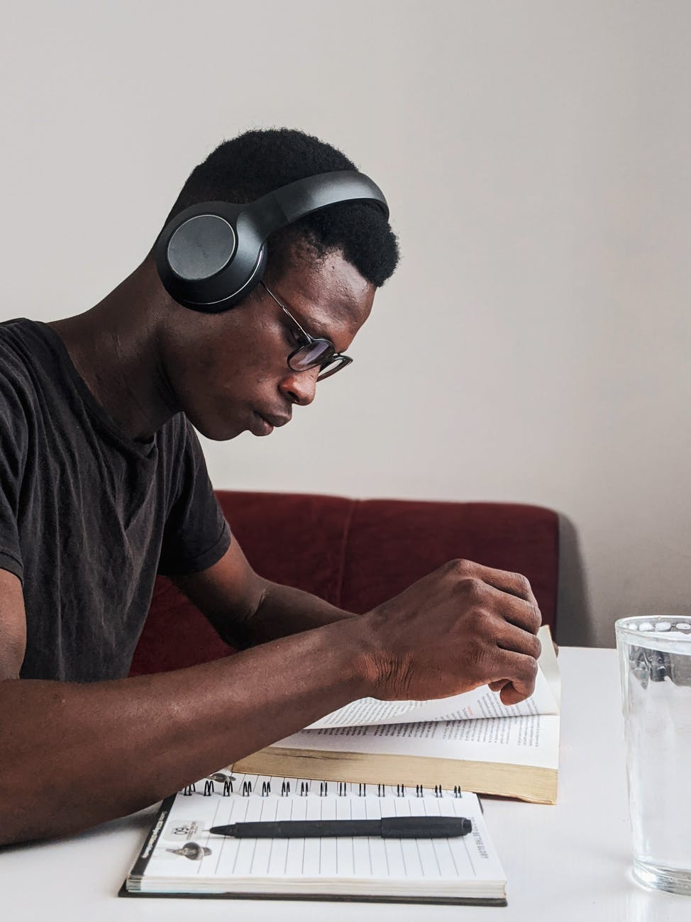 man wearing black crew neck t shirt using black headphones reading book while sitting
