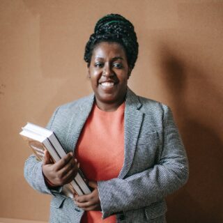 smiling black female teacher with textbooks